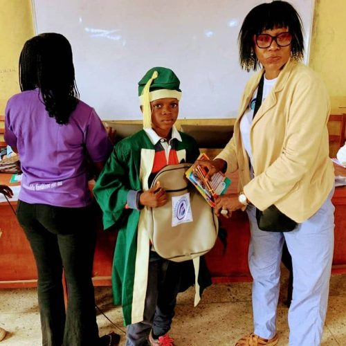 A graduating pupil receiving his backpack and school supplies from a BBSI volunteer