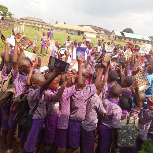 Children proudly holding up their new learning materials